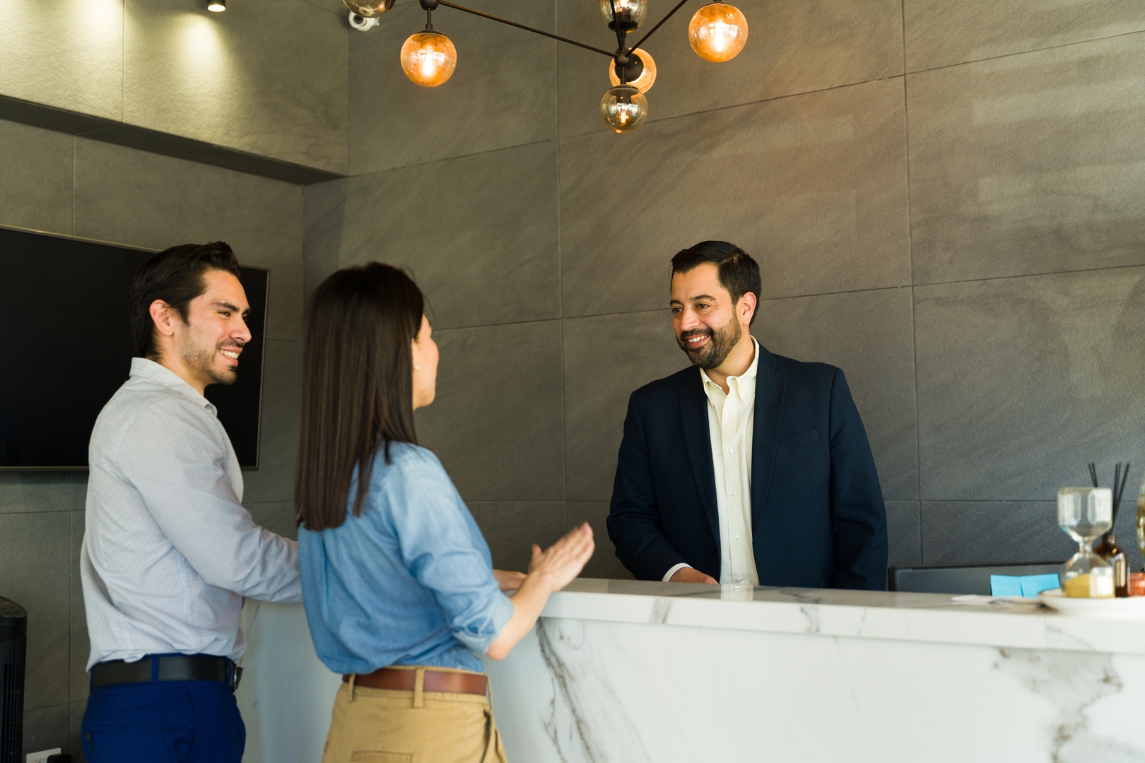 Attractive man working as receptionist and giving directions to some businesspeople in an office